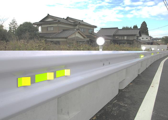 昼間に設置されたガードリフレクターの施工写真。蛍光反射材が日陰で反射する様子。